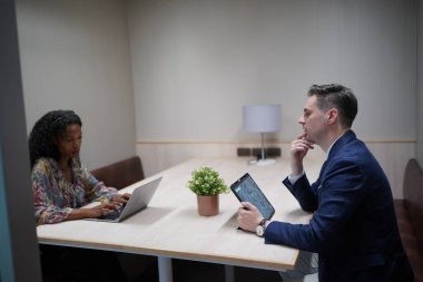 Genç iş adamları ve meslektaşlarının toplantıda laptopta ve dokunmatik kağıtları tartışırken görüntüsü