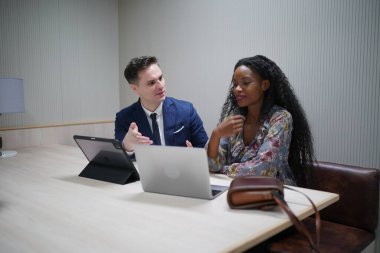 Genç iş adamları ve meslektaşlarının toplantıda laptopta ve dokunmatik kağıtları tartışırken görüntüsü