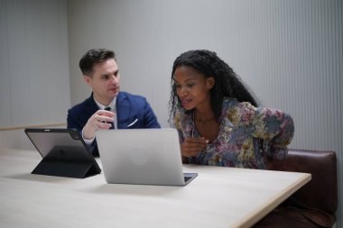 Genç iş adamları ve meslektaşlarının toplantıda laptopta ve dokunmatik kağıtları tartışırken görüntüsü