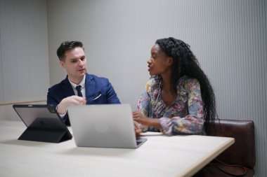 Genç iş adamları ve meslektaşlarının toplantıda laptopta ve dokunmatik kağıtları tartışırken görüntüsü