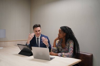 Genç iş adamları ve meslektaşlarının toplantıda laptopta ve dokunmatik kağıtları tartışırken görüntüsü