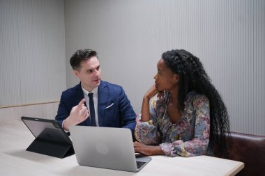 Genç iş adamları ve meslektaşlarının toplantıda laptopta ve dokunmatik kağıtları tartışırken görüntüsü