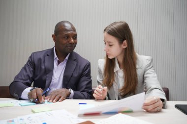 Genç iş adamları ve meslektaşlarının toplantıda laptopta ve dokunmatik kağıtları tartışırken görüntüsü