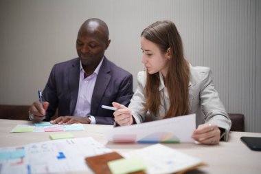 Genç iş adamları ve meslektaşlarının toplantıda laptopta ve dokunmatik kağıtları tartışırken görüntüsü