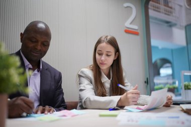 Genç iş adamları ve meslektaşlarının toplantıda laptopta ve dokunmatik kağıtları tartışırken görüntüsü