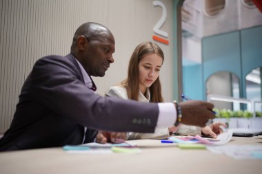 Genç iş adamları ve meslektaşlarının toplantıda laptopta ve dokunmatik kağıtları tartışırken görüntüsü