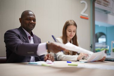 Genç iş adamları ve meslektaşlarının toplantıda laptopta ve dokunmatik kağıtları tartışırken görüntüsü