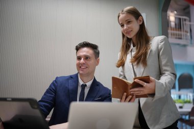 Genç iş adamları ve meslektaşlarının toplantıda laptopta ve dokunmatik kağıtları tartışırken görüntüsü