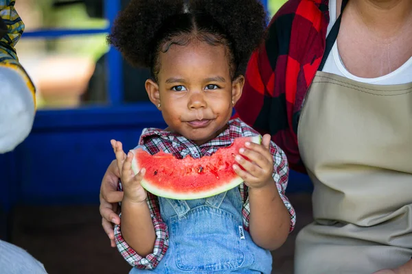 Küçük afro kız organik çiftlikteki fidanlıkta karpuz yemekten hoşlanıyor..