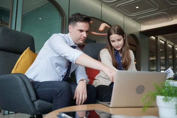 Genç iş adamları ve meslektaşlarının toplantıda laptopta ve dokunmatik kağıtları tartışırken görüntüsü