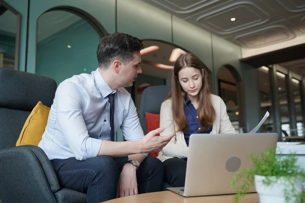 Genç iş adamları ve meslektaşlarının toplantıda laptopta ve dokunmatik kağıtları tartışırken görüntüsü