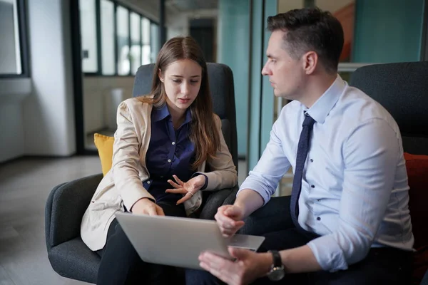 Genç iş adamları ve meslektaşlarının toplantıda laptopta ve dokunmatik kağıtları tartışırken görüntüsü
