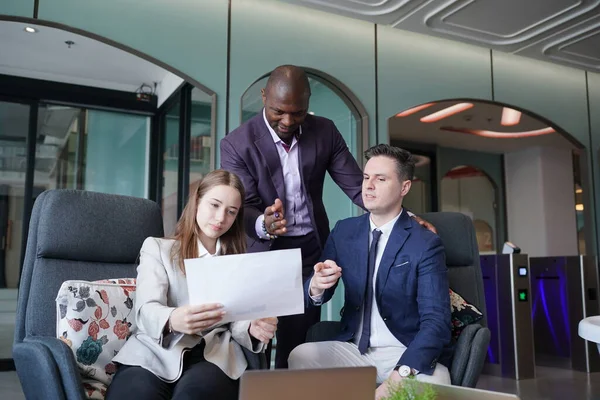 Genç iş adamları ve meslektaşlarının toplantıda laptopta ve dokunmatik kağıtları tartışırken görüntüsü