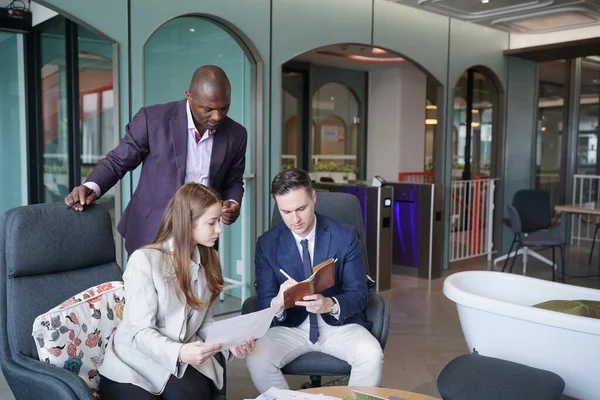 Genç iş adamları ve meslektaşlarının toplantıda laptopta ve dokunmatik kağıtları tartışırken görüntüsü