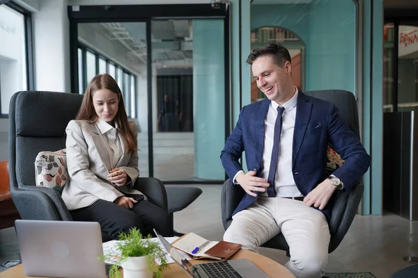 Genç iş adamları ve meslektaşlarının toplantıda laptopta ve dokunmatik kağıtları tartışırken görüntüsü