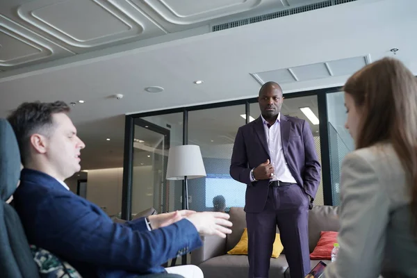 Genç iş adamları ve meslektaşlarının toplantıda laptopta ve dokunmatik kağıtları tartışırken görüntüsü