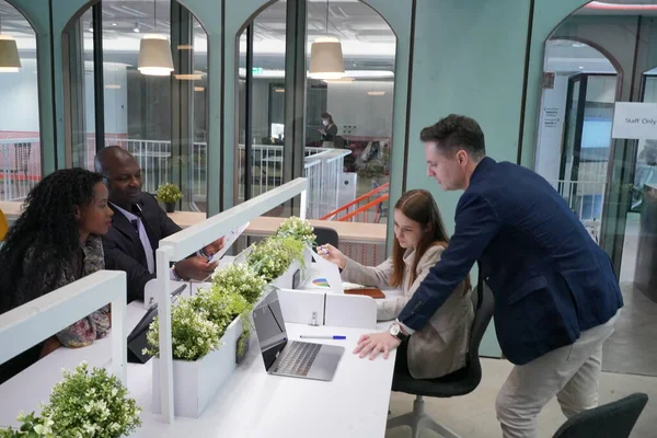 Genç iş adamları ve meslektaşlarının toplantıda laptopta ve dokunmatik kağıtları tartışırken görüntüsü