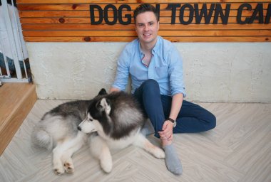 Genç adam yerde yatan köpeğine sarılıyor..