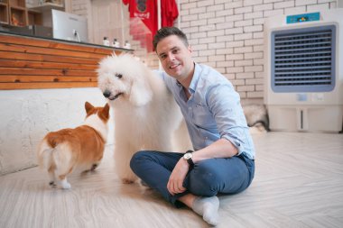 Genç adam yerde yatan köpeğine sarılıyor..