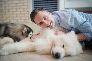 Genç adam yerde yatan köpeğine sarılıyor..