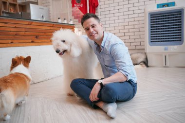 Genç adam yerde yatan köpeğine sarılıyor..