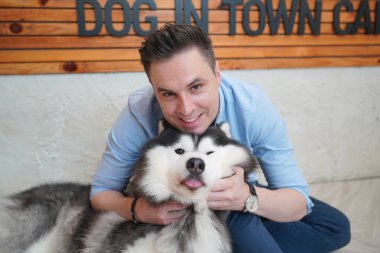 Genç adam yerde yatan köpeğine sarılıyor..