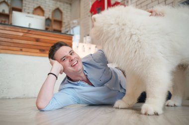 Genç adam yerde yatan köpeğine sarılıyor..