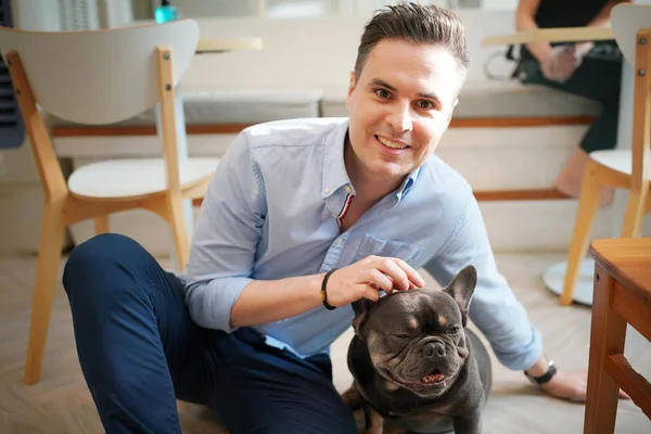 Genç adam yerde yatan köpeğine sarılıyor..