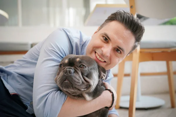 young man hugging his dog lying on floor.