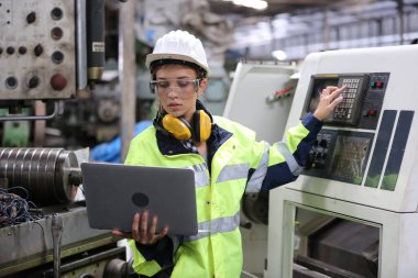 Fabrikada dizüstü bilgisayar kullanan mühendis