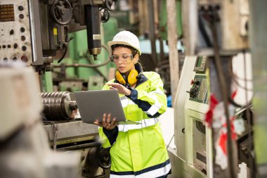 Fabrikada çalışan koruyucu kasklı bir kadın işçi.