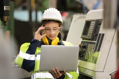 Fabrikada çalışan koruyucu kasklı bir kadın işçi.