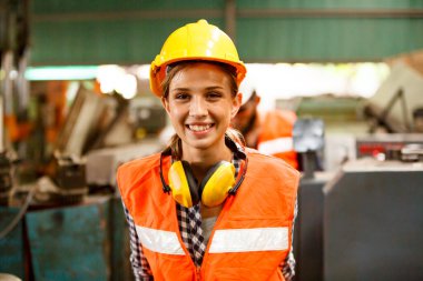 Fabrikada çalışan koruyucu kasklı bir kadın işçi.