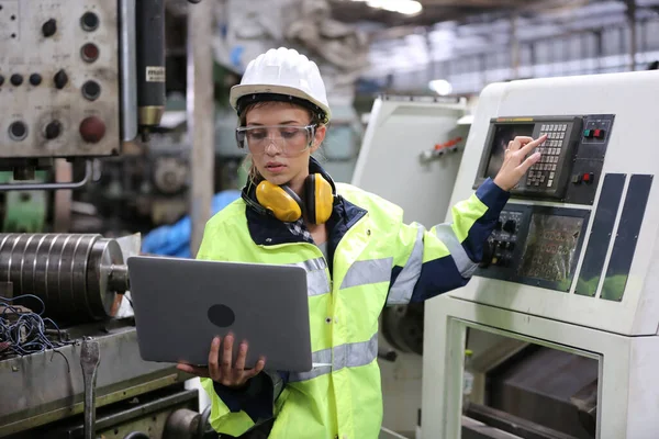 Fabrikada dizüstü bilgisayar kullanan mühendis