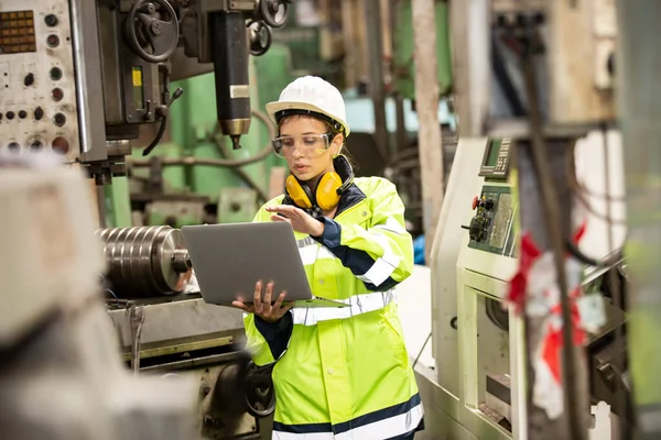 Fabrikada çalışan koruyucu kasklı bir kadın işçi.