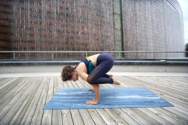 Young sporty attractive woman practicing yoga, doing yoga exercise, Beautiful young woman practicing yoga on wooden terrace.