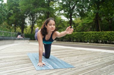 Young attractive woman doing stretching yoga exercise in the park.