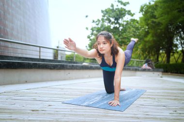 Young attractive woman doing stretching yoga exercise in the park.