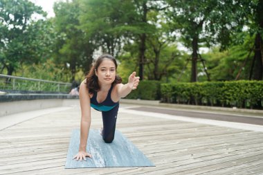 Young attractive woman doing stretching yoga exercise in the park.