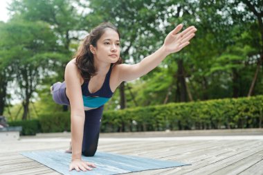 Young attractive woman doing stretching yoga exercise in the park.