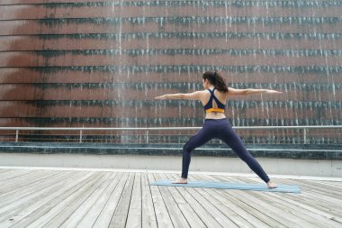 Young attractive woman doing stretching yoga exercise in the park.