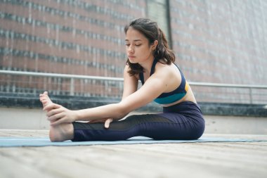 Young attractive woman doing stretching yoga exercise in the park.