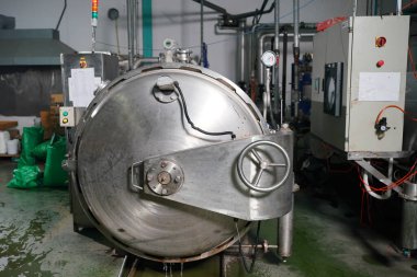 View of reservoires and soft drinks factory interior. worker controlling the work of machine in production line at beverage industry.