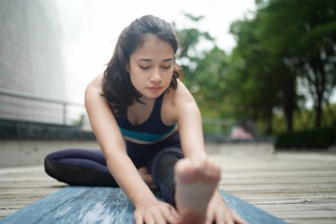 Young attractive woman doing stretching yoga exercise in the park.