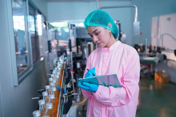 worker controlling the work of machine in production line at beverage industry.
