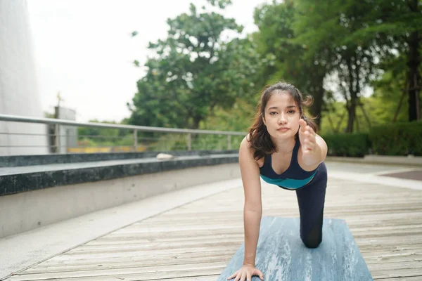 Young attractive woman doing stretching yoga exercise in the park.