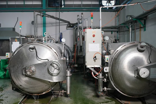 View of reservoires and soft drinks factory interior. worker controlling the work of machine in production line at beverage industry.