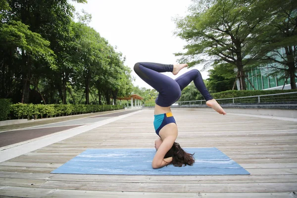 Young sporty attractive woman practicing yoga, doing yoga exercise, Beautiful young woman practicing yoga on wooden terrace.