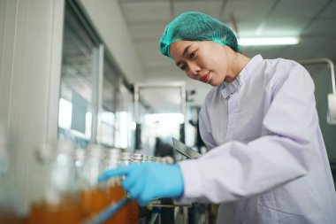 worker controlling the work of machine in production line at beverage industry.