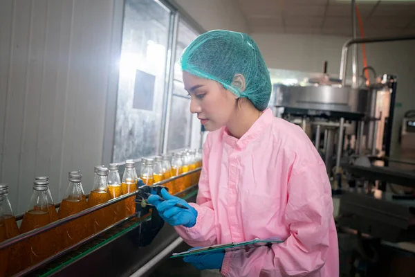 Asian worker labor working in food and beverage for drink industry factory with hygiene work fruit juice production line inspector staff. Inspect Beverage Process Check Production Line Conveyor